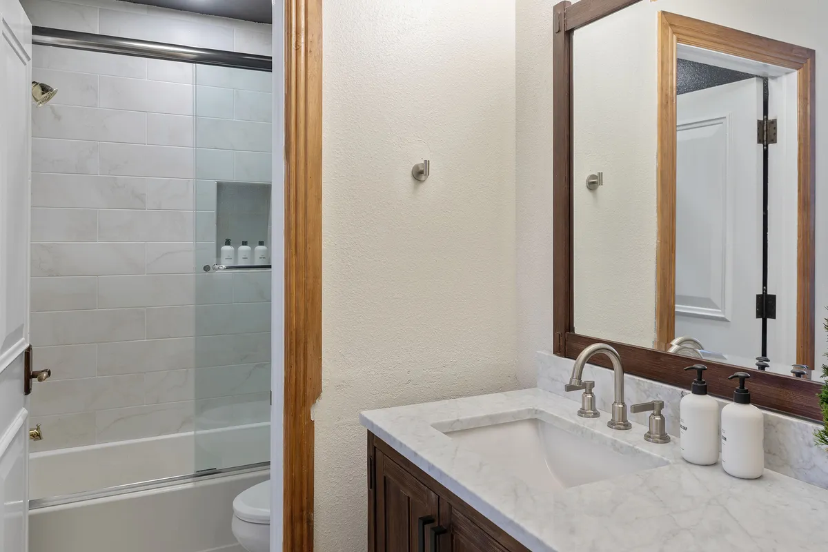 A modern, calming bathroom featuring a vanity with a sink, large mirror, and a shower area with glass doors. The clean lines and soothing palette evoke a sense of spa-like relaxation and rejuvenation.